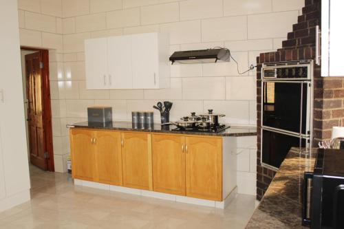 a kitchen with wooden cabinets and a stove at EMPEROR LODGE AND TOURS in Germiston