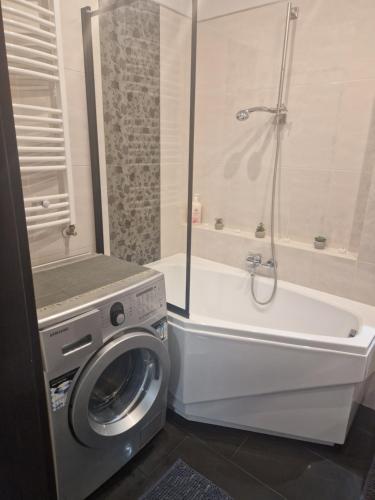 a bathroom with a washing machine and a bath tub at Apartament Blisko Natury in Olsztyn