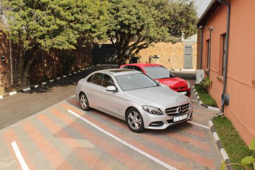 a silver car parked in a parking lot next to a red car at EMPEROR LODGE AND TOURS in Germiston