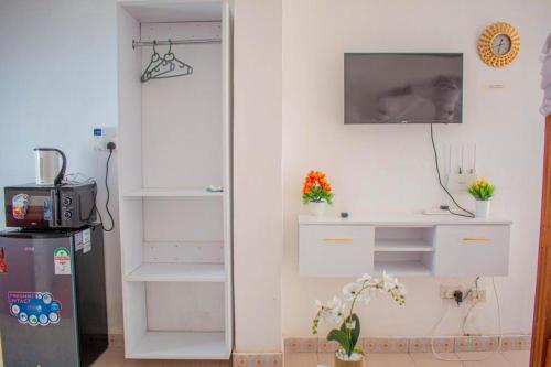 Pokój z białymi szafkami i telewizorem na ścianie w obiekcie Emap Homes-Urban studios w mieście Kilifi