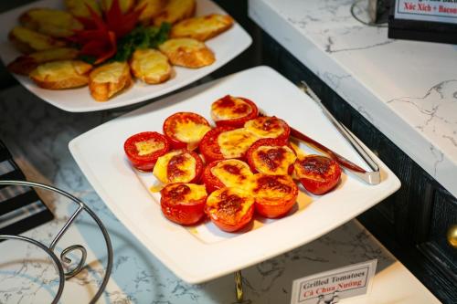 a plate of food with tomatoes on a table at Scent Premium Hotel in Hanoi
