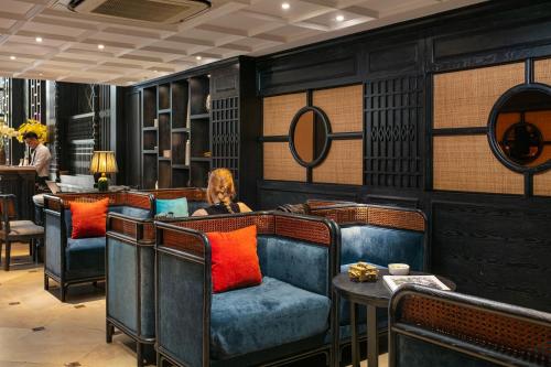 a woman sitting in a room with chairs and a table at Scent Premium Hotel in Hanoi