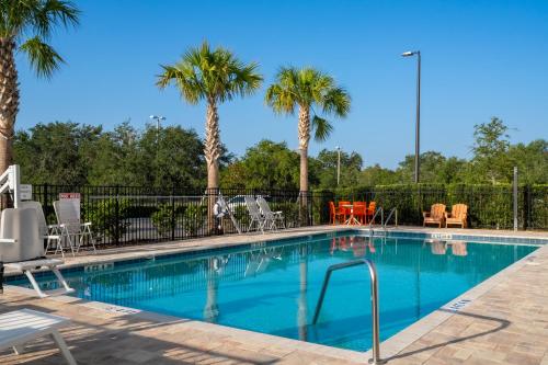 una piscina con sillas y palmeras en SPOT X Hotel Orlando Intl Dr by The Red Collection en Orlando