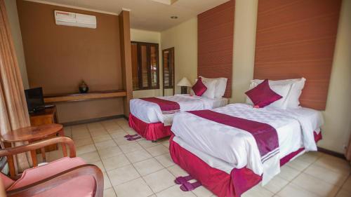 Cette chambre d'hôtel comprend 2 lits avec des draps rouges et blancs. dans l'établissement Kalicaa Villa Resort, Tanjung Lesung, à Tanjung Lesung