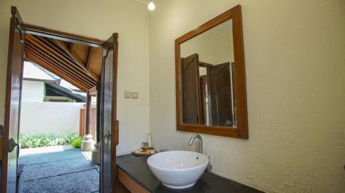 a bathroom with a sink and a mirror on the wall at Kalicaa Villa Resort, Tanjung Lesung in Tanjung Lesung