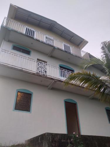 a white building with a balcony and a palm tree at Casa Gonzalez 