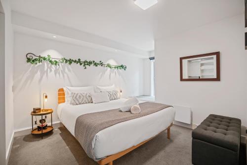a white bedroom with a bed and a chair at Lakeside Living - 1 Bedroom Alpine Apartment 1 in Queenstown