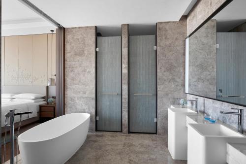 a bathroom with a tub and two sinks and a bed at Wenzhou Airport Marriott Hotel in Wenzhou
