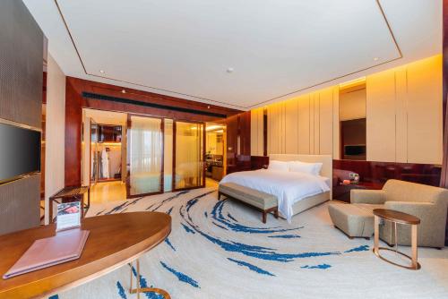 a bedroom with a bed and a living room at Ramada By Wyndham Huizhou South in Huizhou