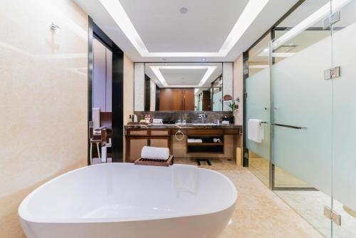 a bathroom with a white tub and a sink at Ramada By Wyndham Huizhou South in Huizhou