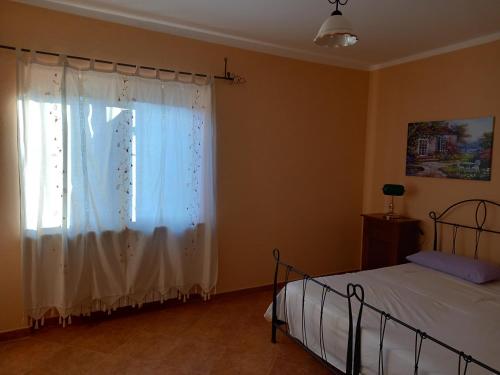 a bedroom with a bed and a window with white curtains at La casa delle fate in Giave