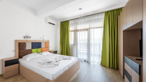 a bedroom with a large bed with green curtains at SnS Apartament Regal in Mamaia