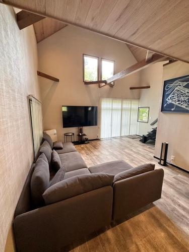 a large living room with a couch and a flat screen tv at ペット可｜自然に囲まれながらサウナやBBQ｜最大８名｜The No.10河口湖　 in Fujikawaguchiko