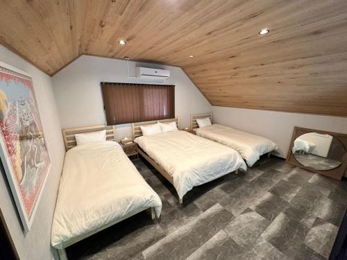 two beds in a small room with wooden ceilings at ペット可｜自然に囲まれながらサウナやBBQ｜最大８名｜The No.10河口湖　 in Fujikawaguchiko