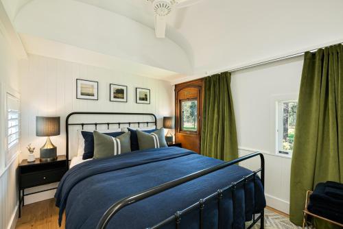 a bedroom with a blue bed and green curtains at The Station Hunter Valley in Pokolbin
