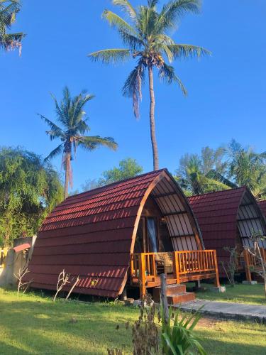 ein Haus mit einem Strohdach und Palmen in der Unterkunft Blue Moon Meno in Gili Meno