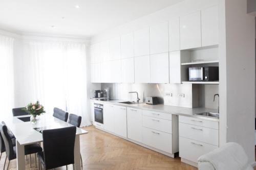 une cuisine avec des armoires blanches et une table avec des chaises dans l'établissement Luminous Apartment golden quarter, à Marseille