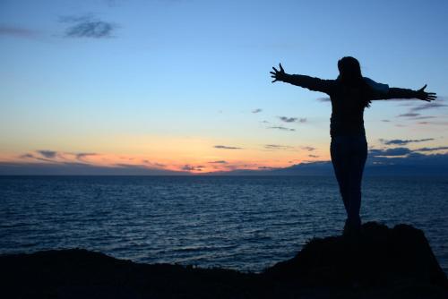 a woman standing on a rock in front of the ocean at Hotel Calachica Las Negras in Las Negras