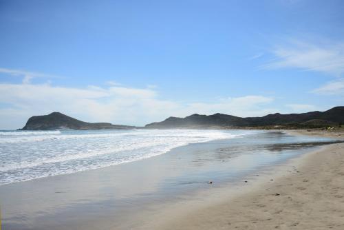 a sandy beach with a view of the ocean at Hotel Calachica Las Negras in Las Negras