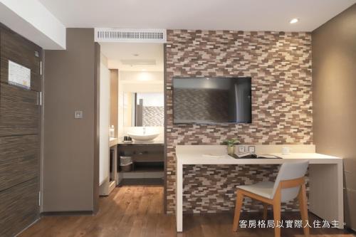 uma casa de banho com um lavatório e uma televisão na parede em Talmud Hotel Yizhong em Taichung