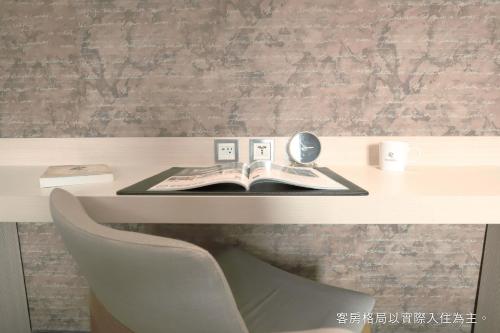 a desk with a book and a mirror and a chair at Talmud Hotel Yizhong in Taichung