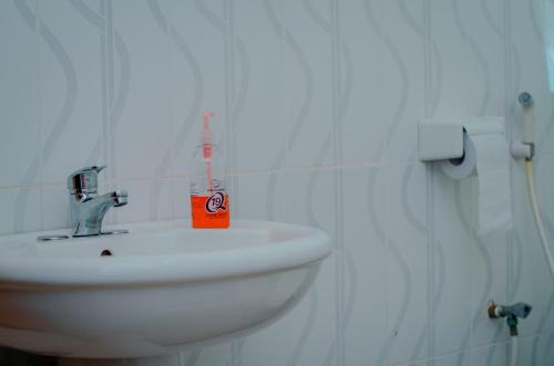 a white bathroom with a sink and a soap bottle at Hostel Kiliwood in Moshi