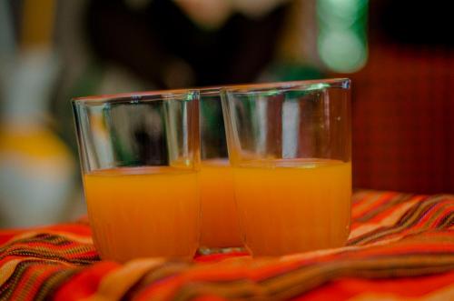 two glasses of orange juice sitting on a table at Hostel Kiliwood in Moshi