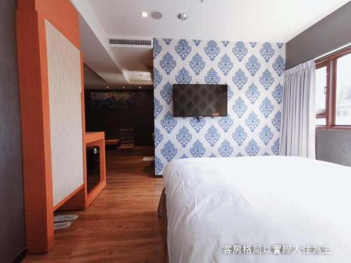a bedroom with a bed and a tv on a wall at Talmud Hotel Yizhong in Taichung