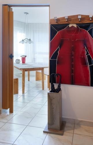 a painting of a red jacket on a wall next to a table at KeramikArt-Wohnung in Pécs