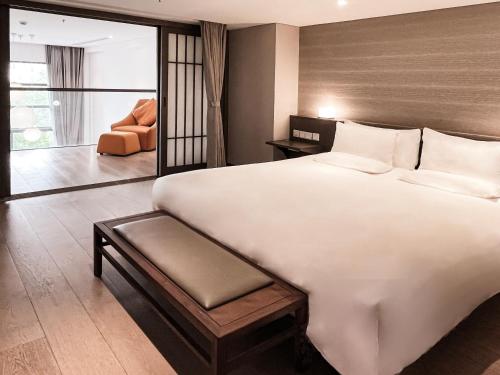 a bedroom with a large white bed and a chair at Novotel Suites Shanghai Hongqiao in Shanghai