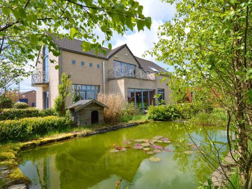 ein Haus mit einem Teich davor in der Unterkunft Delightful Villa in Sourbrodt with Swimming Pool Terrace in Weismes