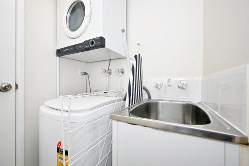 a small kitchen with a sink and a washing machine at Mooloolaba 2 B/R Getaway - Perfect location ZD5 in Mooloolaba