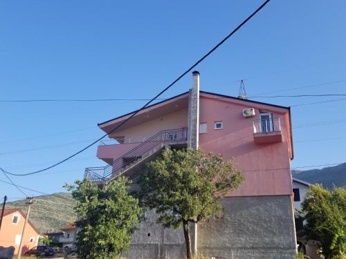 a pink building with a tree in front of it at Apartmani Vasković in Trebinje
