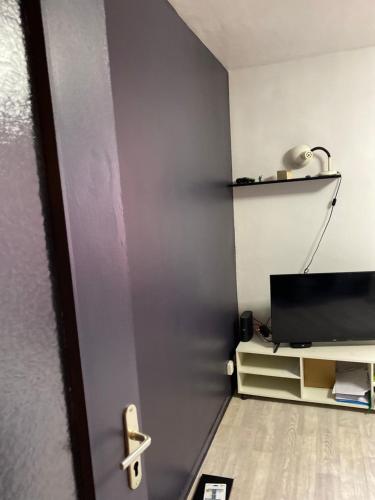 een deur naar een kamer met een televisie en een lamp bij Studio in Manosque