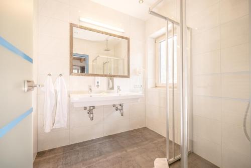 een witte badkamer met een wastafel en een spiegel bij Harakiri lodgings und ApresSki in Mayrhofen