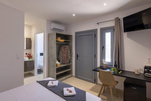 - une chambre avec un lit, un bureau et une table dans l'établissement Chrysonisos Suites with Sunset & Seaviews near Kini, à Áno Sýros