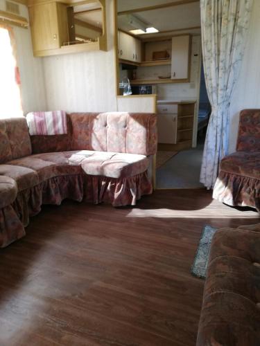 a living room with a couch and a kitchen at Kempings Mežmalas in Usma