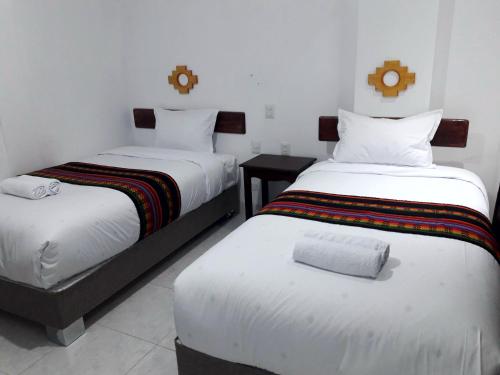 2 letti in una camera d'albergo con tavolo di PAKARINA HOTEL a Machu Picchu