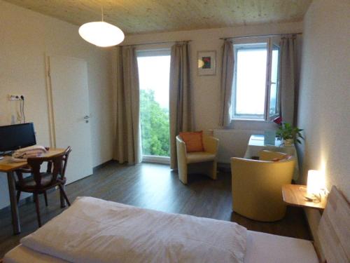 a bedroom with a bed and a table and a desk at Hotel Hohe Flum in Schopfheim