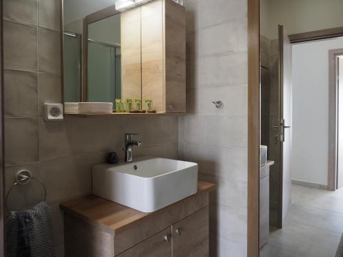 een badkamer met een witte wastafel en een spiegel bij Melissinos Beachfront Apartments in Kómi