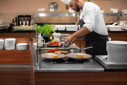 a chef preparing food in a restaurant kitchen at Spa Resort Tree of Life in Lázně Bělohrad