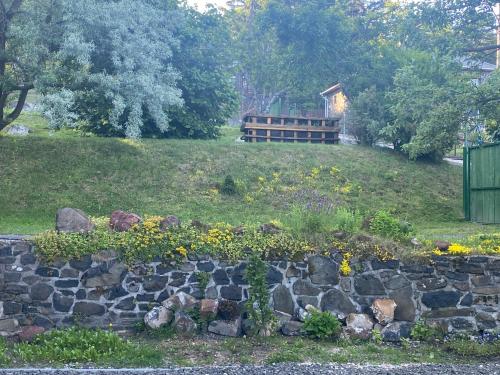a stone retaining wall with flowers in front of a house at Lilakő Apartman in Mátraszentimre