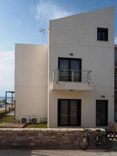 a bike parked in front of a white building at Melissinos Beachfront Apartments in Kómi