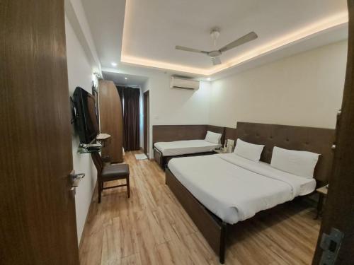 a bedroom with a bed and a chair and a television at Alba Premier, Indore in Indore