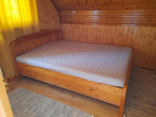 a small bed in a wooden cabin with a mattress at Harmónia Vendégház 100 méterre az Igali gyógyfürdőtől in Igal