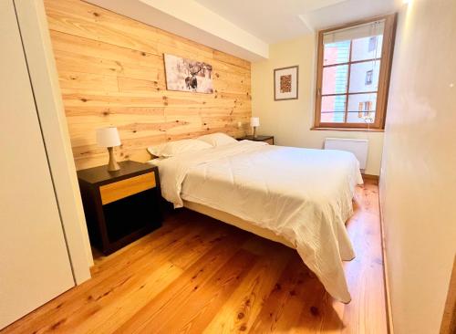 a bedroom with a bed and a wooden wall at T2 au cœur du centre historique de Briançon #1 in Briançon