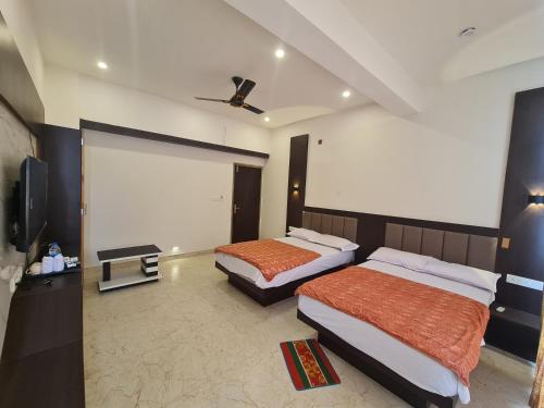 a bedroom with two beds and a flat screen tv at The Nalanda Heritage in Rājgīr