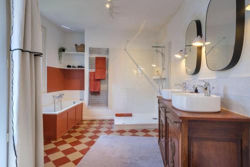 uma casa de banho com 2 lavatórios e uma banheira. em Appartement avec son patio dans centre historique de Bourg em Bourg-sur-Gironde