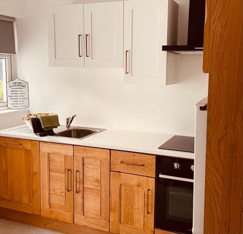 a kitchen with wooden cabinets and a sink at Harbour View Killybegs in Killybegs