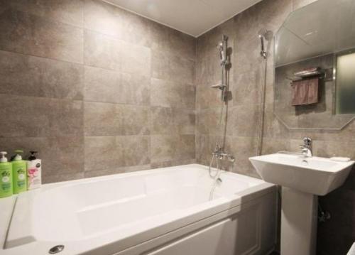 a bathroom with a white tub and a sink at Hotel Days A in Busan